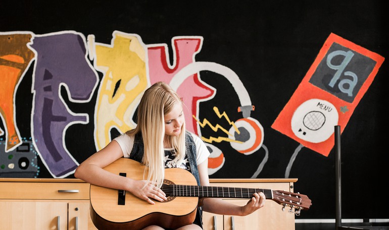 En flicka som spelar akustisk gitarr