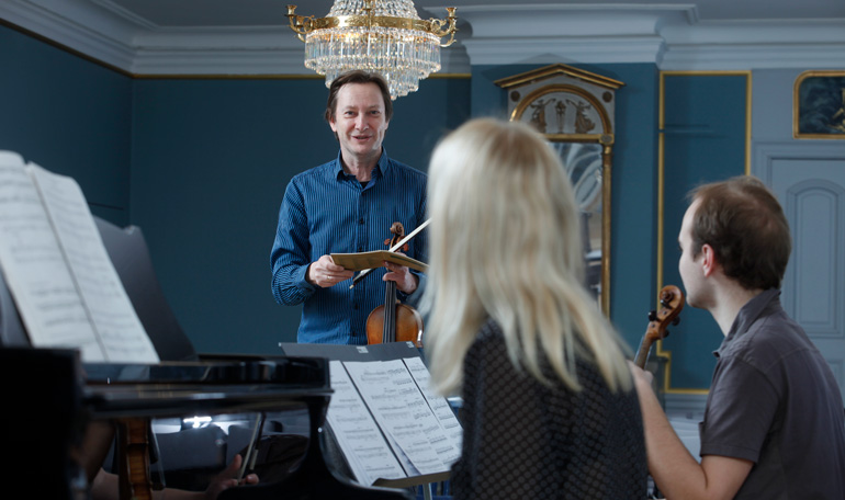 Lärare med två studenter i konsertsalen på Edsbergs slott.